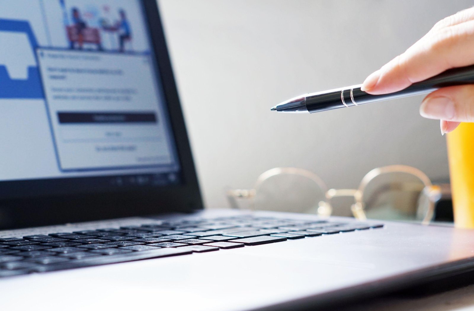 Person pointing a pen on a working laptop screen